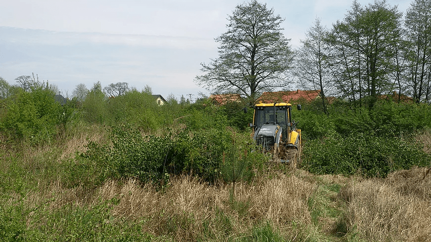 koparka schowana za krzakami