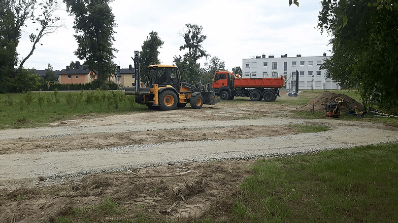 ukończona ścieżka na tle koparki i ciężarówki